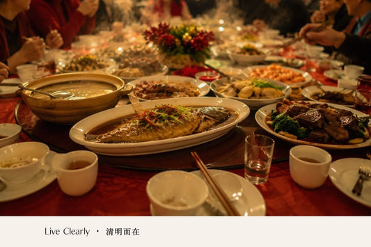 A table filled with shared dishes during a family meal, with people gathered around.